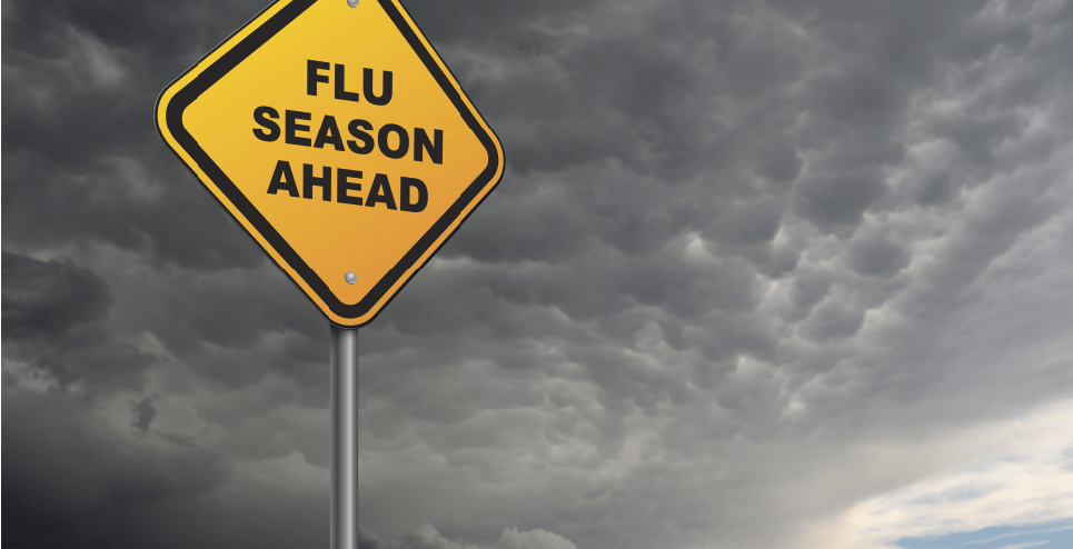 Yellow road sign reading 'Flu Season Ahead' against a cloudy sky, emphasizing the importance of flu prevention and vaccination