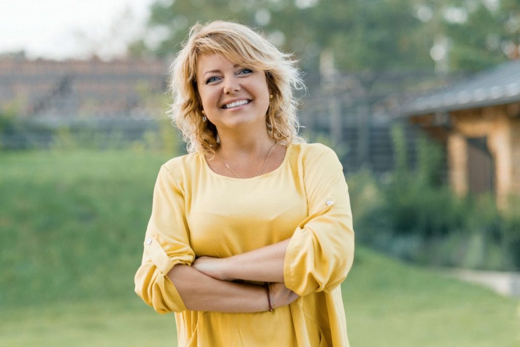 woman in yellow shirt standing outside smiling