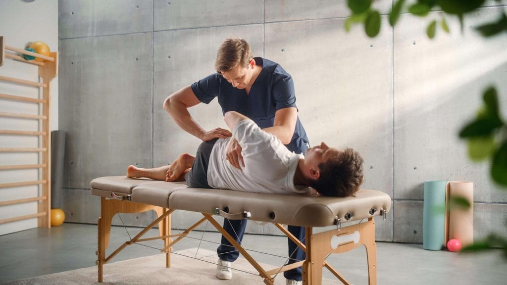 A man on a massage table receiving physical therapy