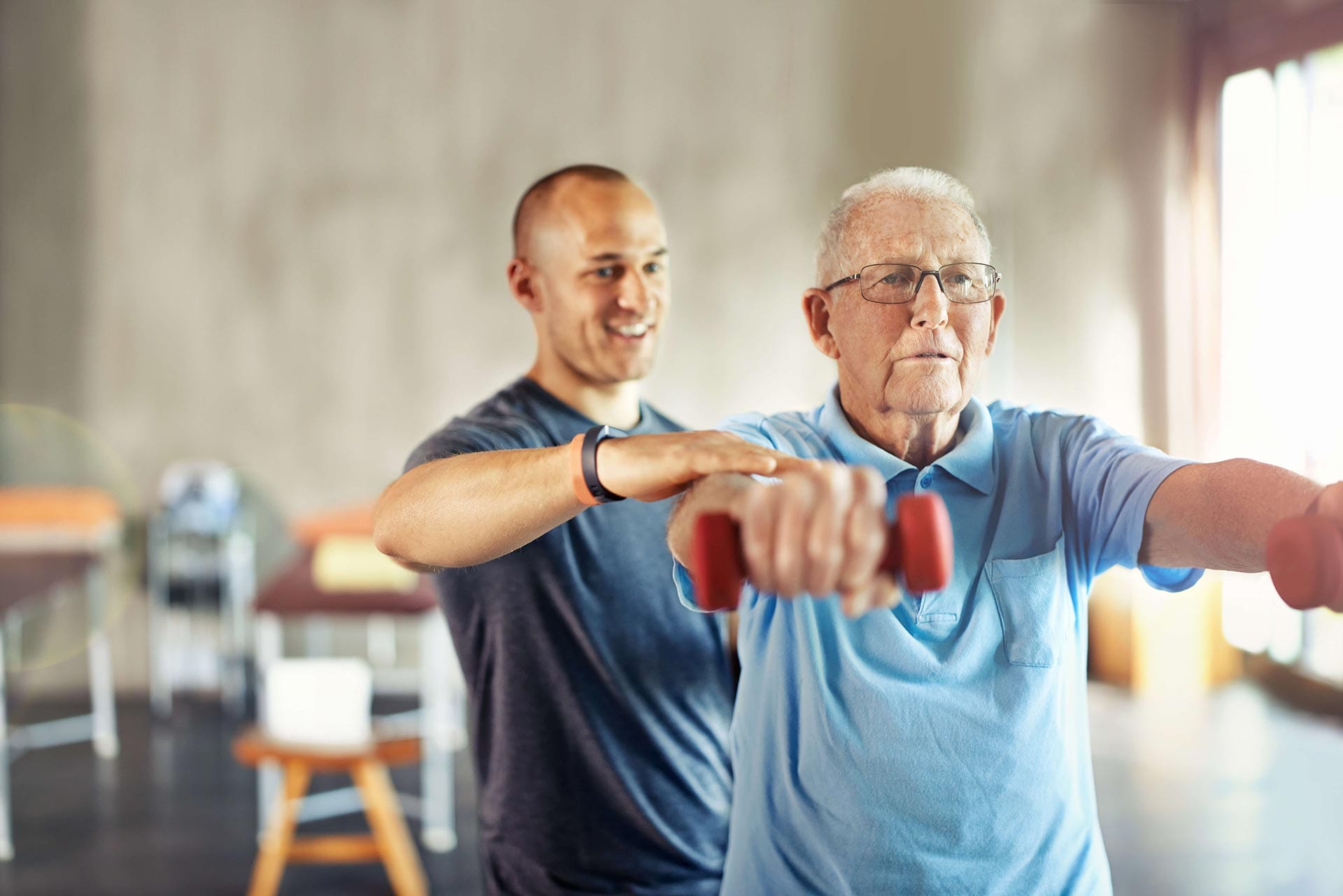A retired gentleman lifting weights with a physical therapist